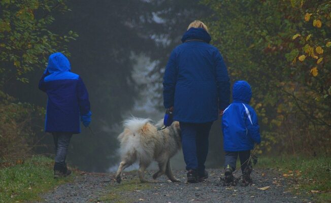 Sieviete pastaigājas ar diviem bērniem un suni